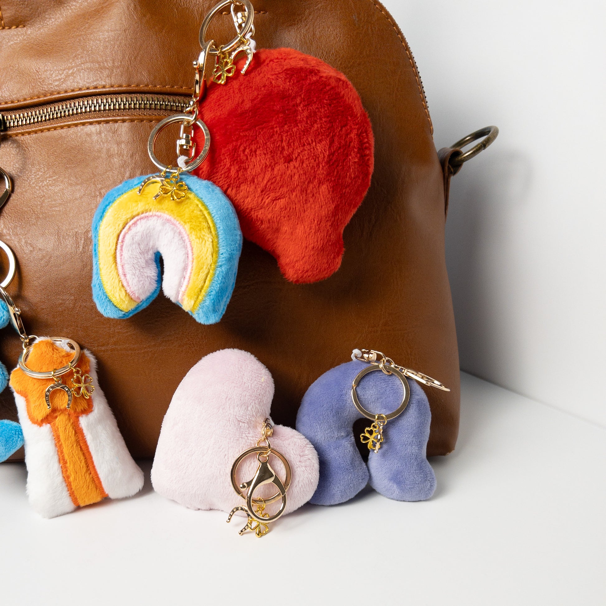 Assortment of colorful plush horseshoe bag charms displayed on a brown leather handbag