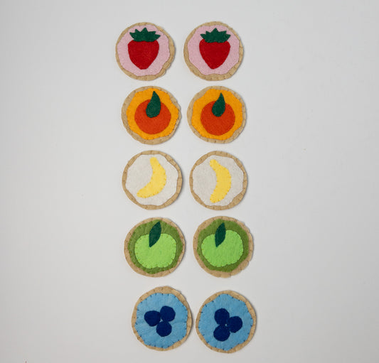 Hand-sewn felt cookies with colorful fruit designs arranged for a matching game