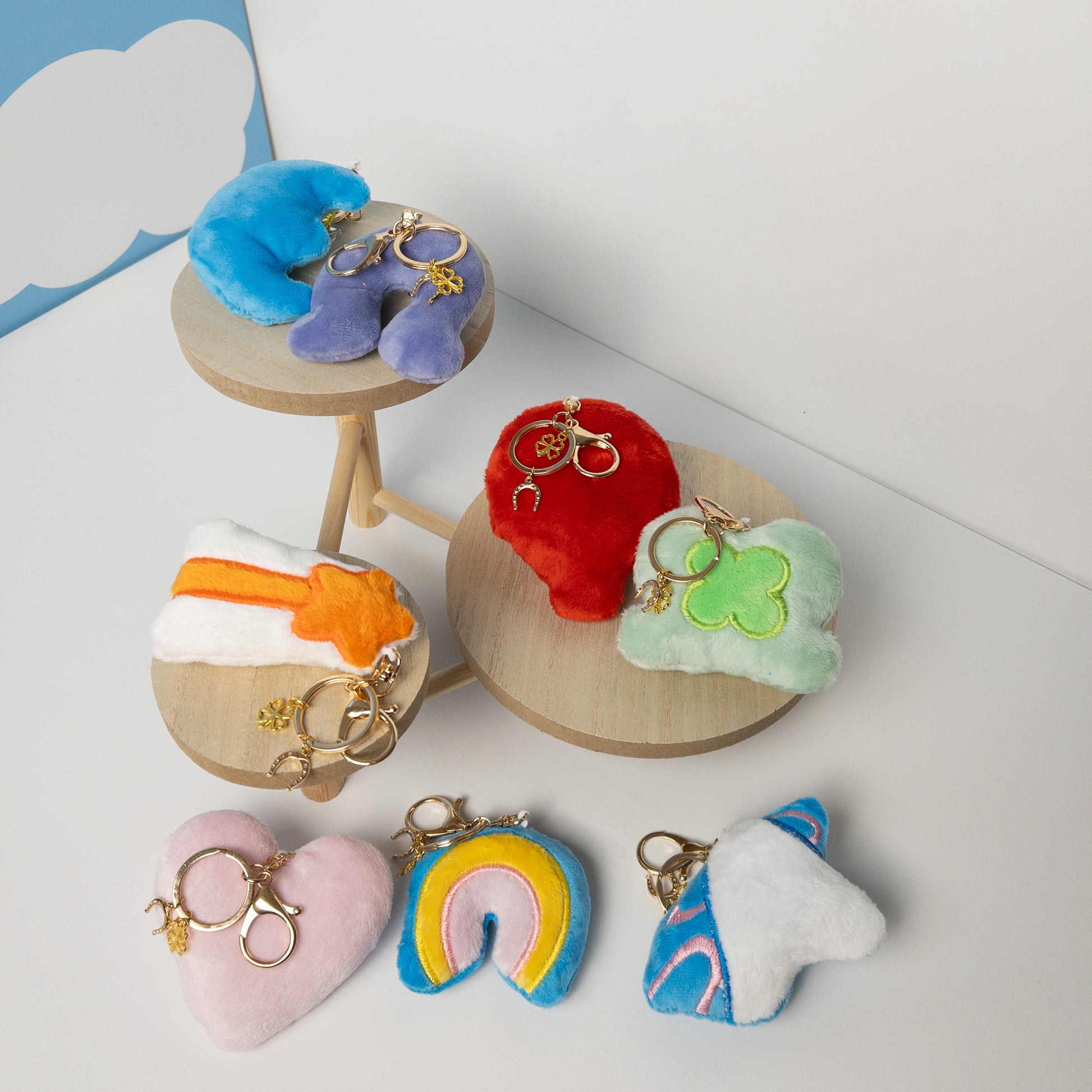 Assortment of whimsical plush bag charms including white unicorn with pink and blue details displayed on a brown leather handbag