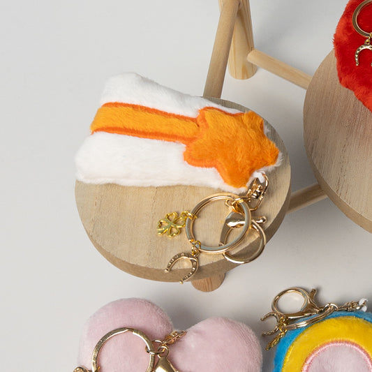 Closeup of orange and white plush shooting star bag charm with gold hardware and mini clover accent