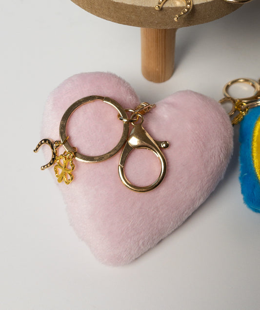 Closeup of soft pink plush heart bag charm with gold hardware and mini heart accent